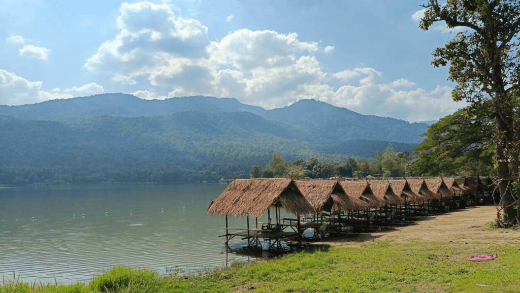 Huay Tueng Thao Reservoir with small huts lining the shore.