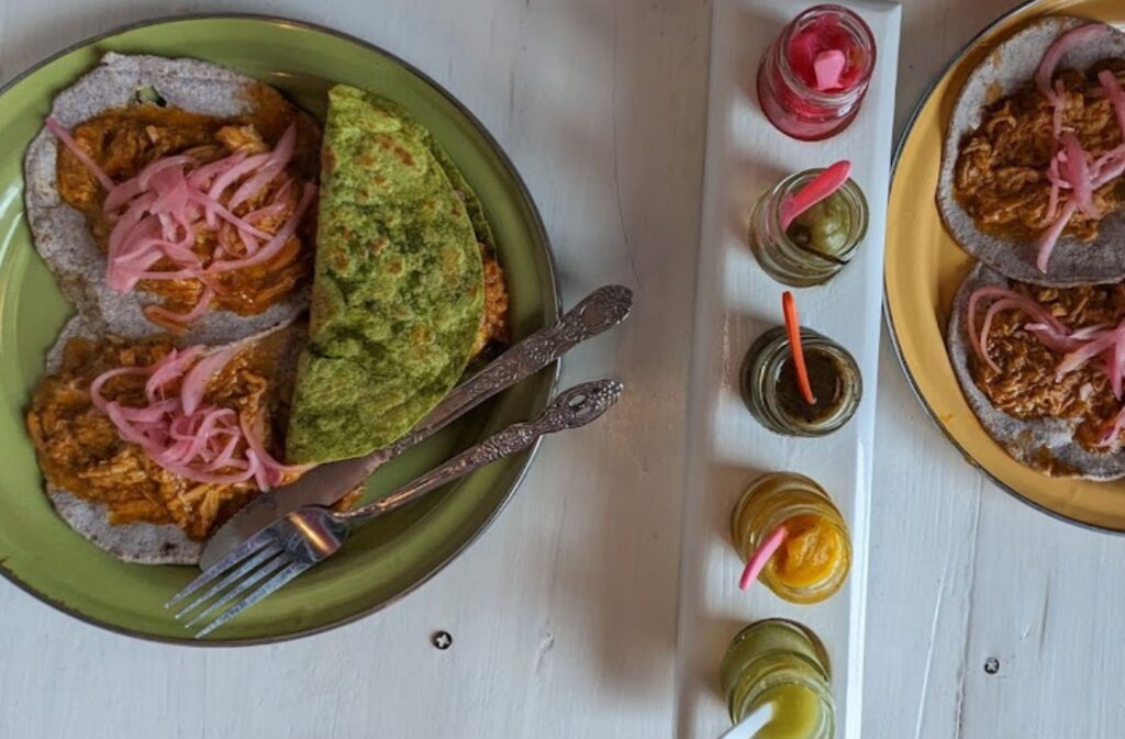 two plates of tacos and sauces on tables at achiote cochinita pibil, san cristobal de las casas