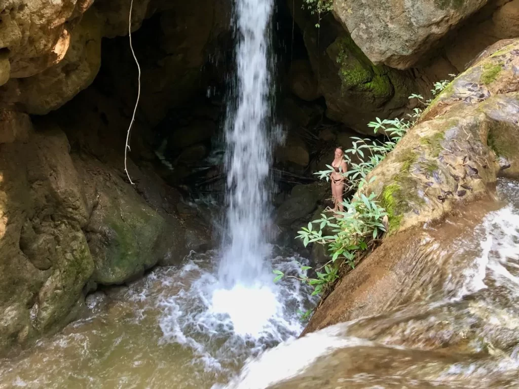 girl at the foot of hua chang waterfall in pai, thailand