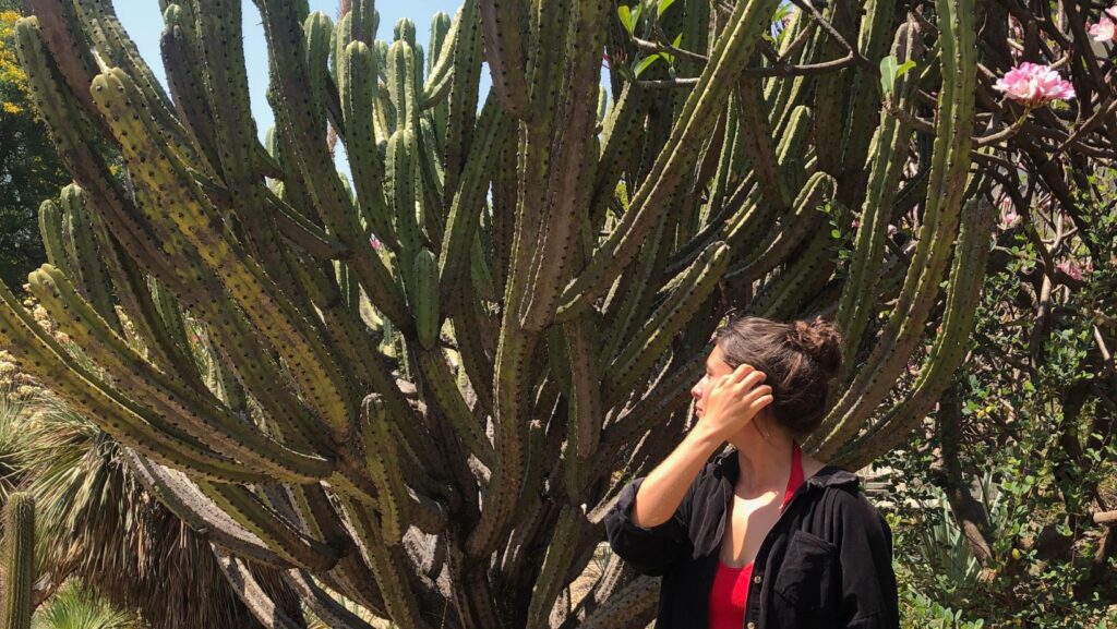 jules from real talk travel standing in front of cactus at Jardín Etnobotánico de Oaxaca