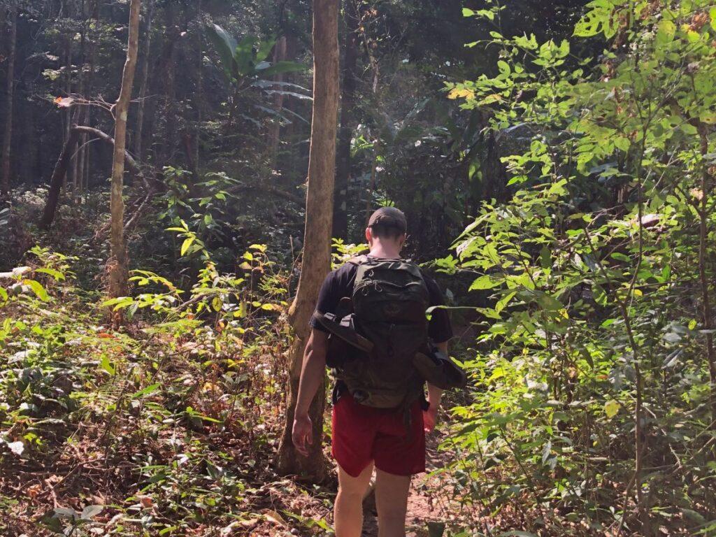 marius walking through the forest on trek to mae yen waterfall in pai