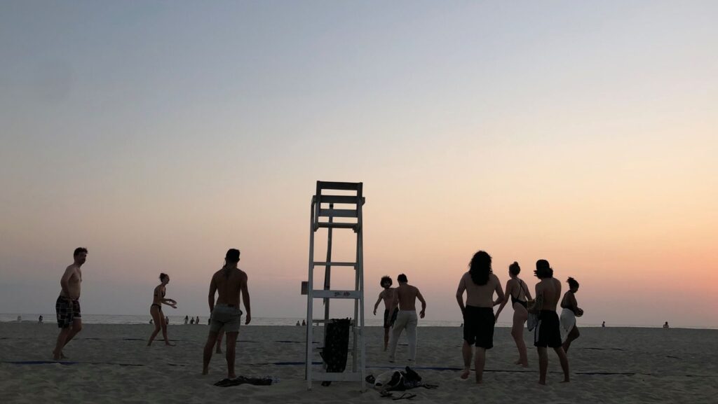 a silhouette of people playing volleyball at la punta in puerto escondido at sunset