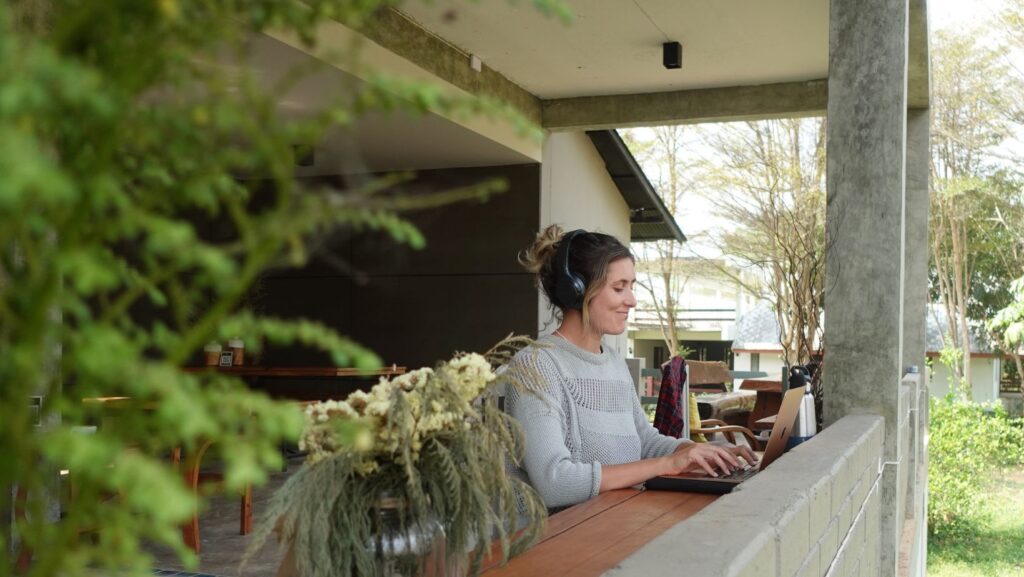 photo of girl from Real Talk Travel working on laptop in green, leafy cafr at Northern Soul Riverside BBQ in Pai, Thailand