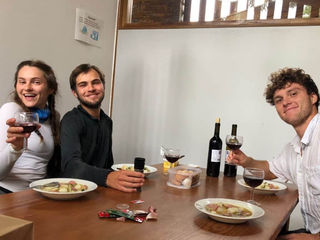 three pilgrims enjoying meal in albergue on the camino de frances, best budget tip