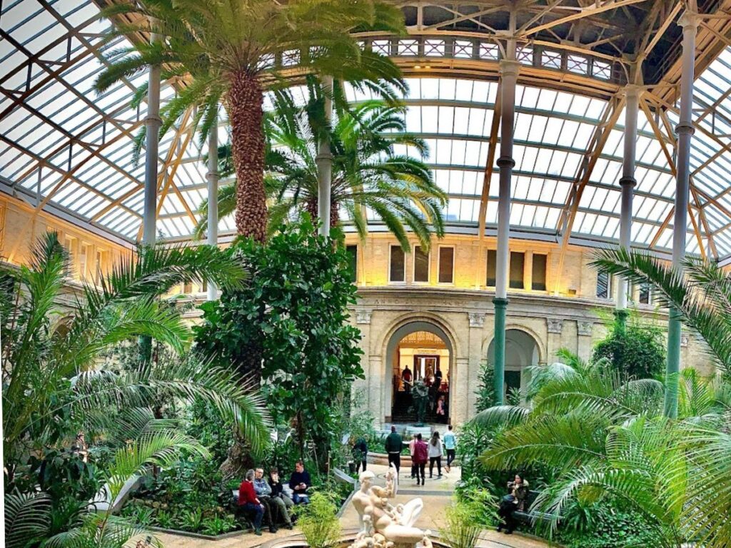 inside NY Calsberg Glyptoteket in Copenahgen, lots of plants and greenhouse roof