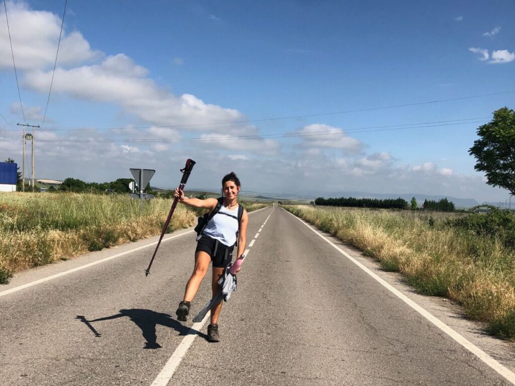 jules from real talk travel posing on camino de santiago with hiking sticks