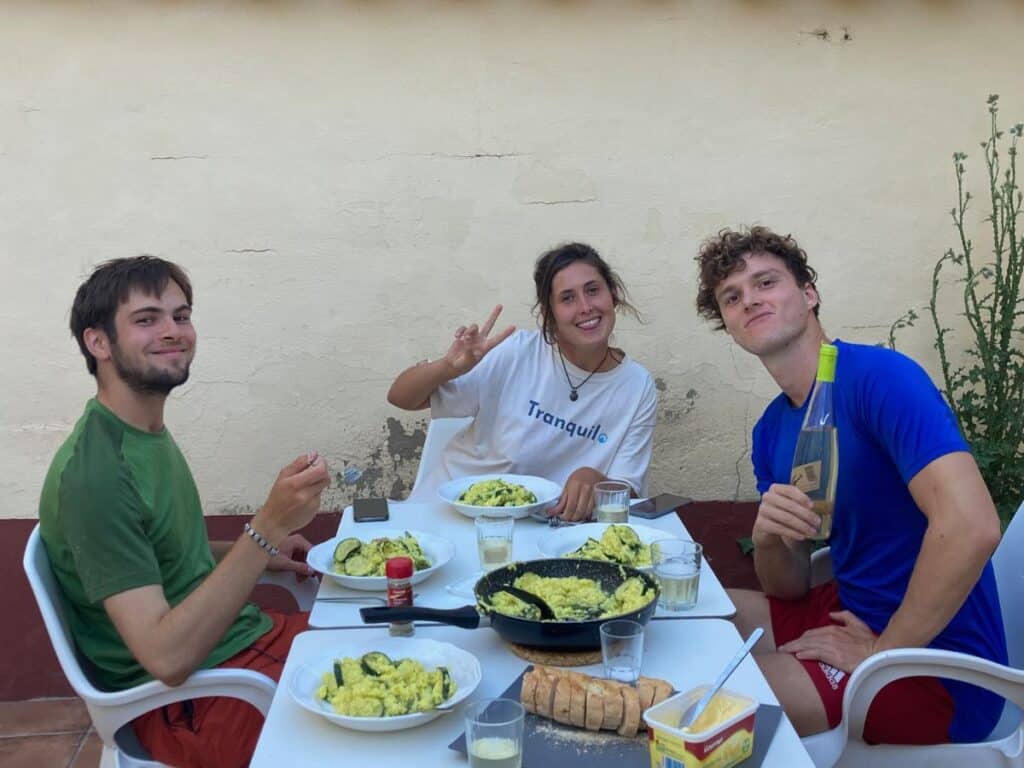 group of three people enjoying homecooked meal on camino de frances, low budget