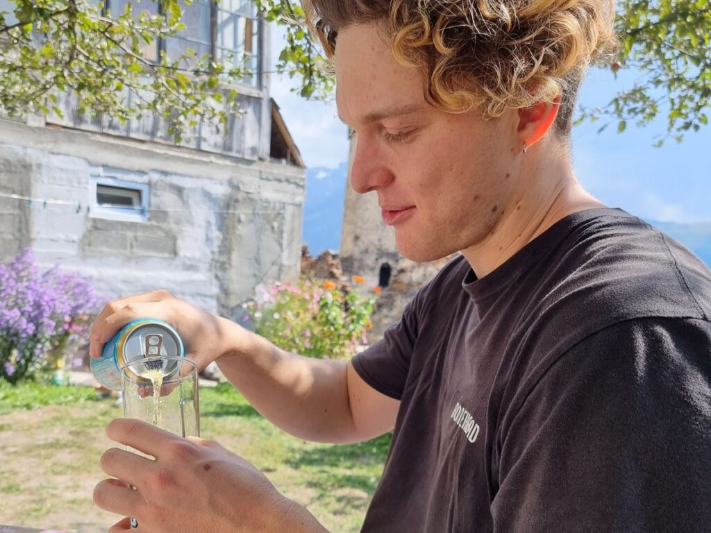 man pouring a beer on hike