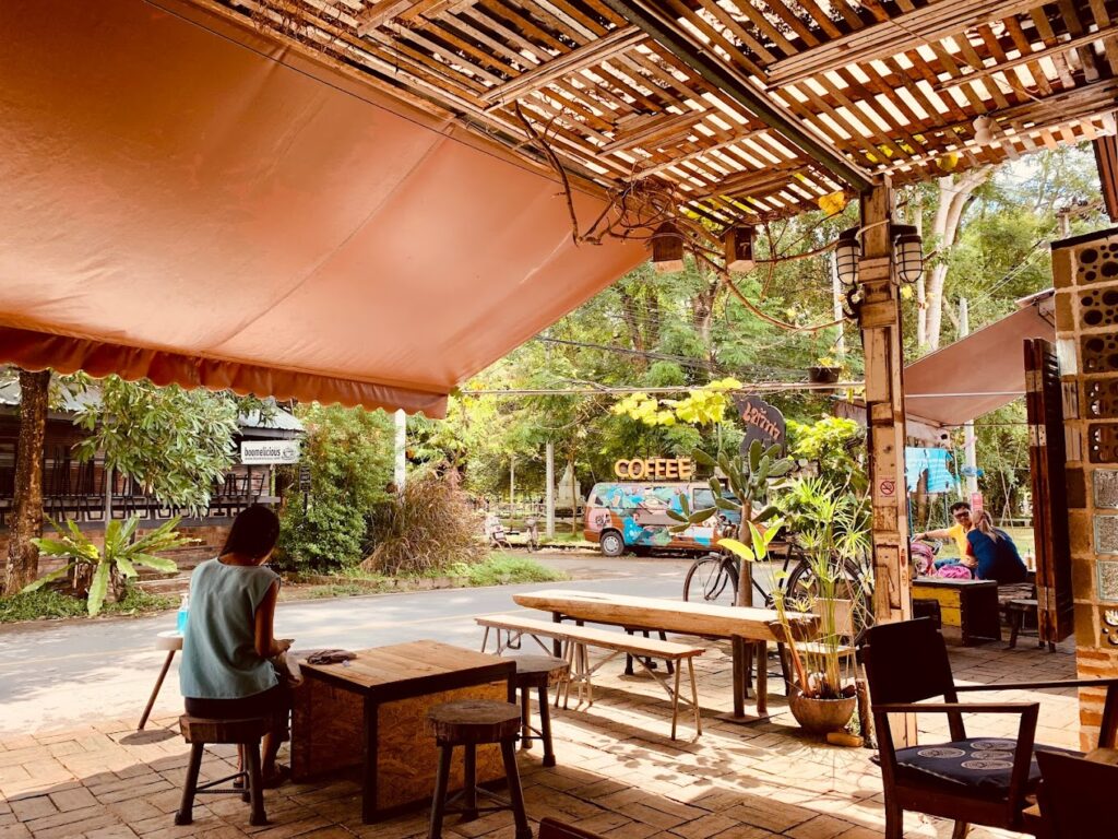 a girl drinking coffee in outside seating area of Khaotha Coffee, Pai near Bodhi Tree Playground, best coffee shop to relax in