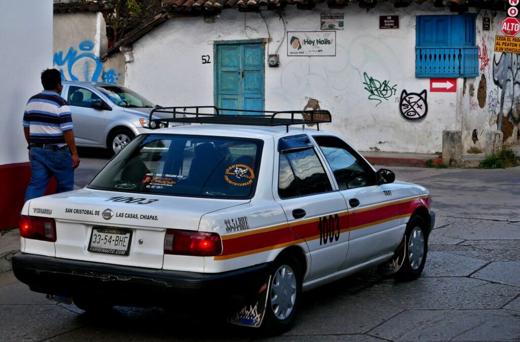 white and red taxi driving in san cristobal de las casas street