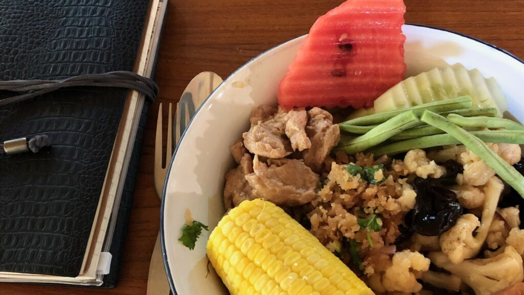 a bowl of watermelon, rice, vegetables served at Wat Pa Tam Forest Monastery, Thailand