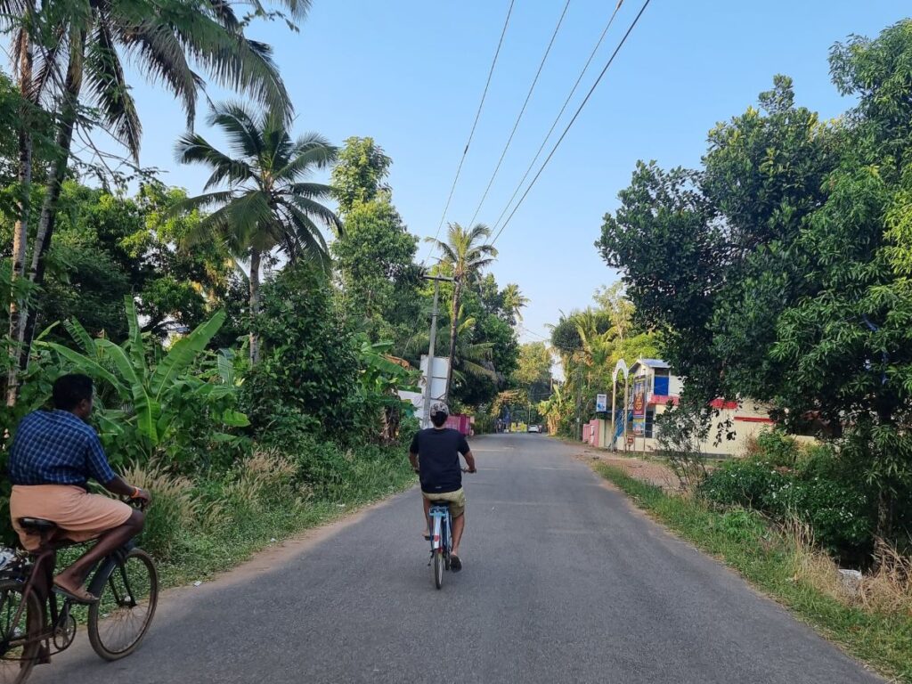 two people cycling through green, quiet streets on Munroe Island, Kerala