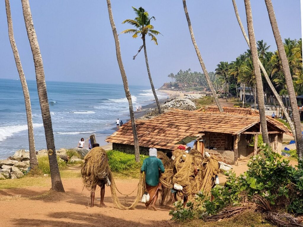 four fisherman carrying nets on black sand beach varkala, kerala