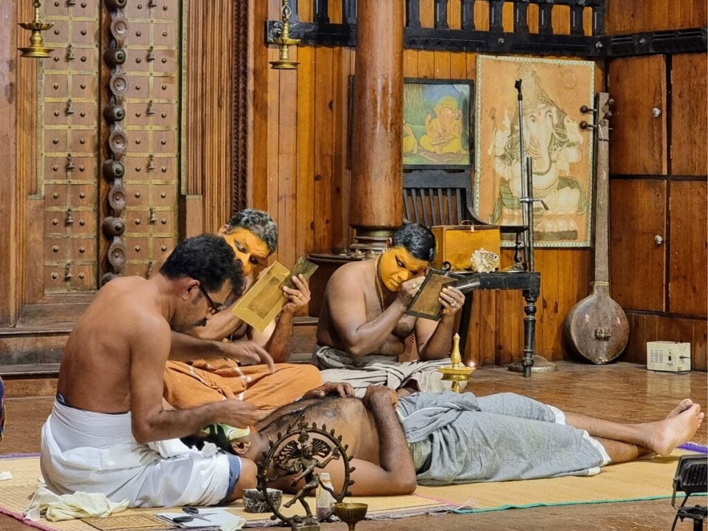 Three performers putting on their make up at Kerala Kathakali Center in Fort Kochi