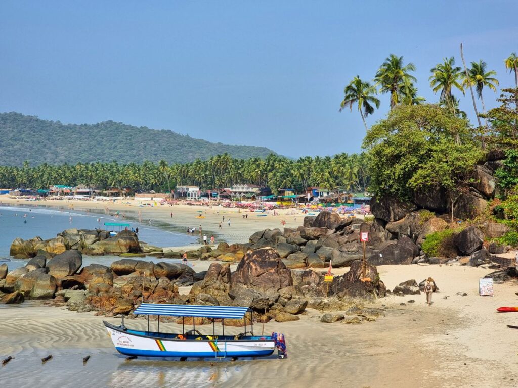 Wide shot of palolem Beach, Goa with palm trees and fishermen boats in the water