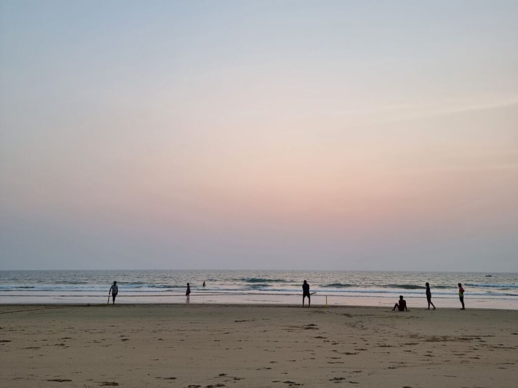 five men playing cricket on Gokarna Beach near Revibe Hostel