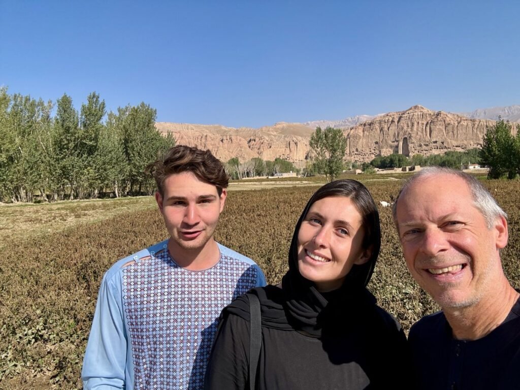 Three tourists smile in front of Buddha of Bamyan Afghanistan