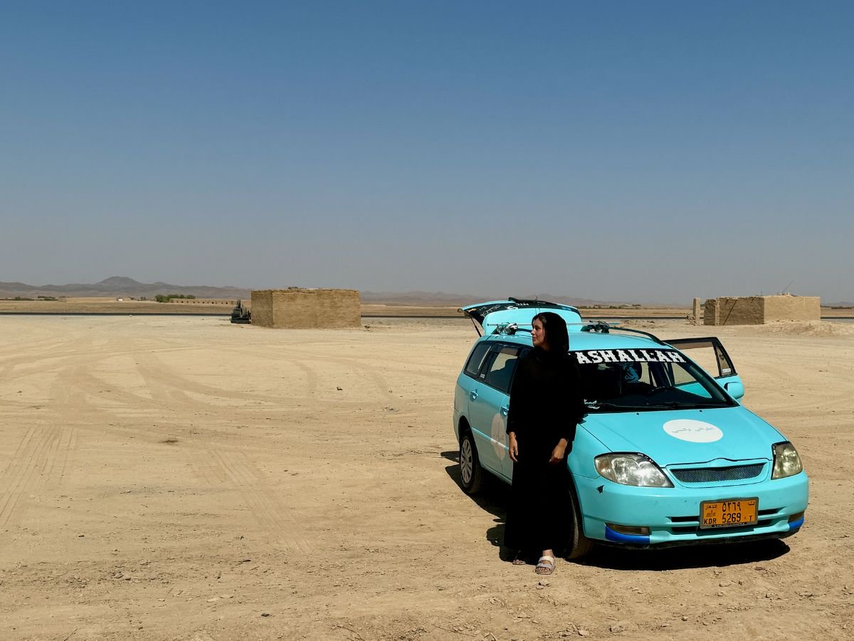Jules from Real Talk Travel standing next to car on road from Kandahar to Kabul, Afghanistan