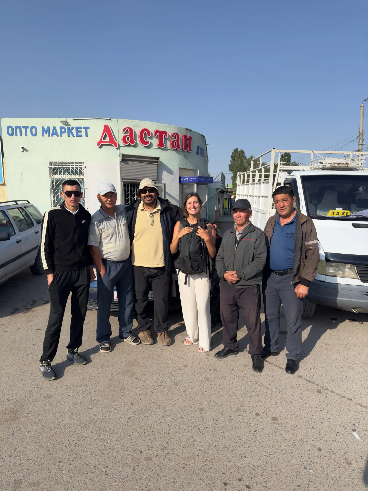 Four taxi drivers standing with travellers in Kochkor, Kyrgyzstan