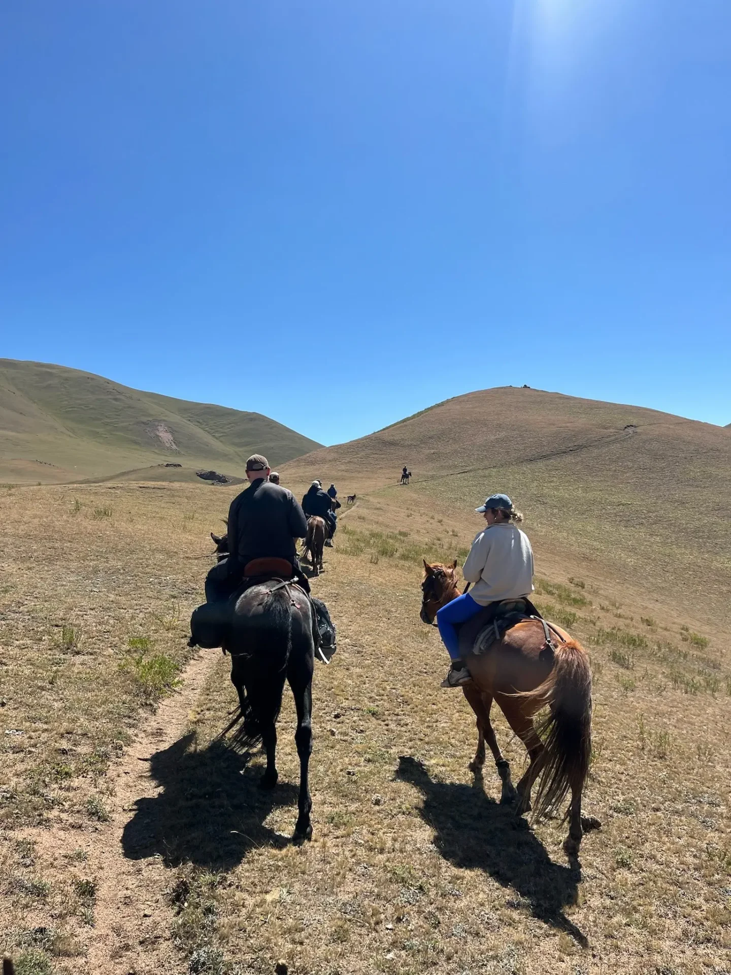 Two travellers riding on horses on Song-Kul lake horse trek