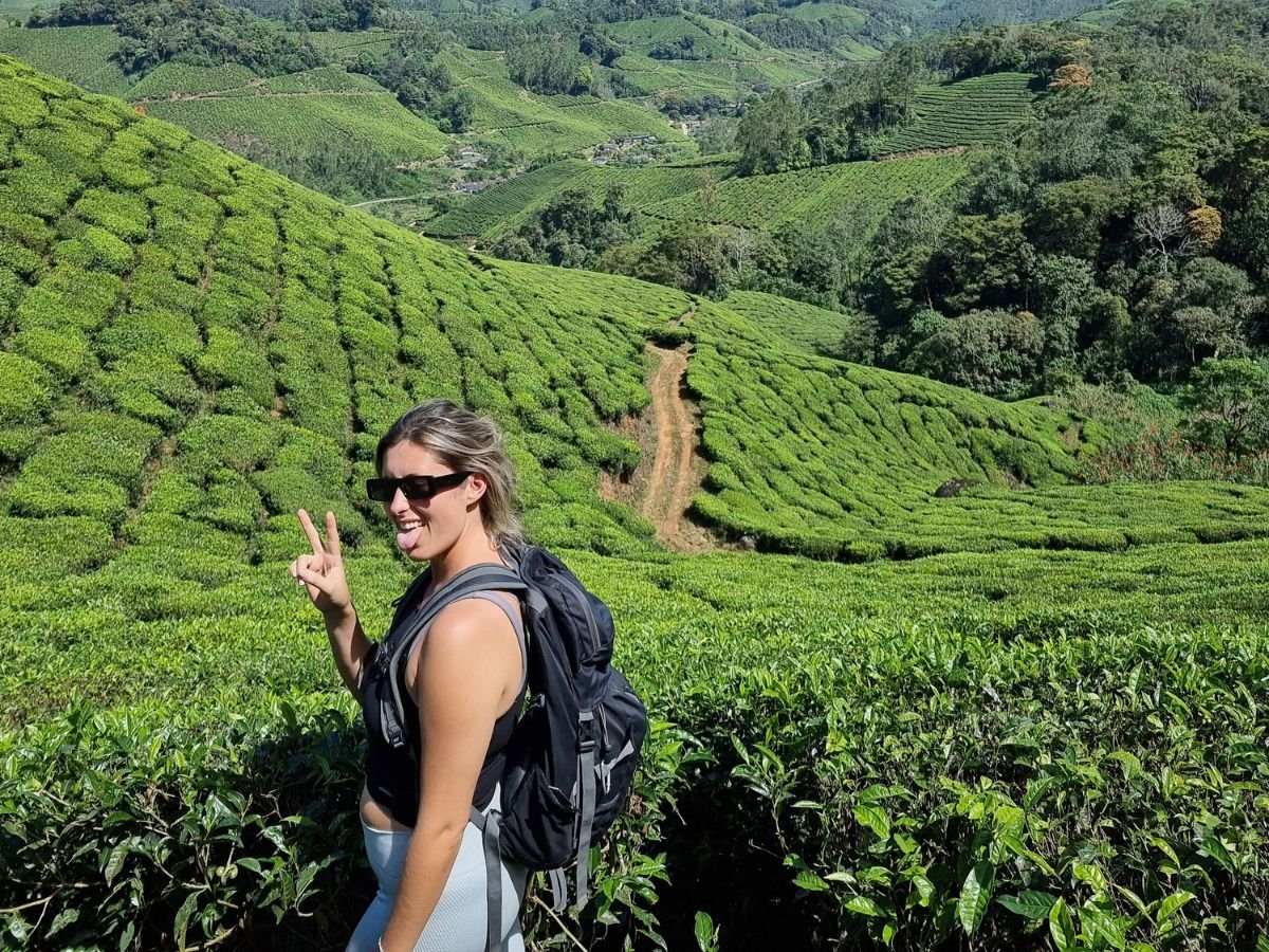 Solo female traveller standing in vibrant green tea fields in Munnar, Kerala